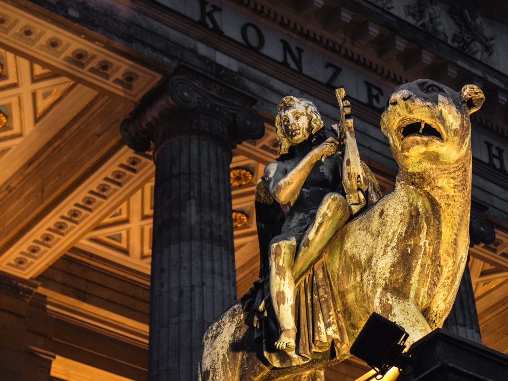 alt="Bronze lion and angel statue in front of the Berlin Concert Hall"